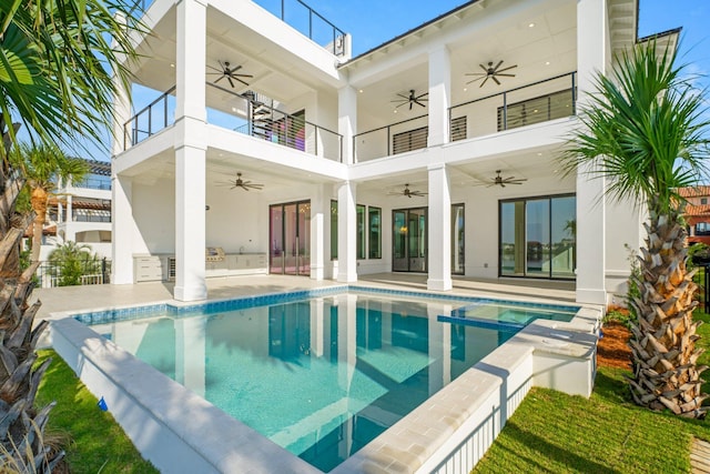 back of property with an outdoor kitchen, a balcony, and a patio area