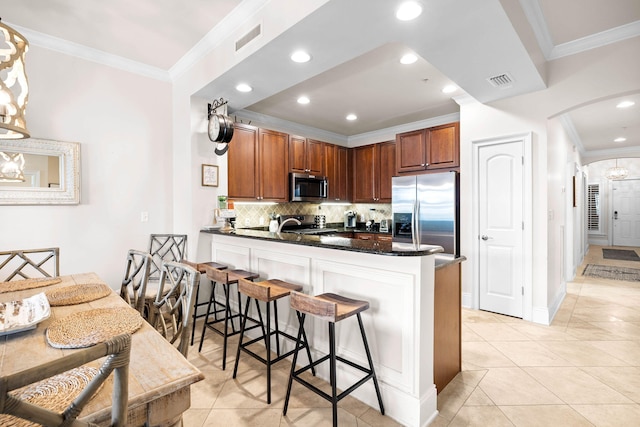 kitchen featuring a kitchen breakfast bar, light tile patterned flooring, kitchen peninsula, and appliances with stainless steel finishes