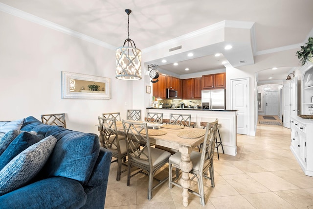 dining room with a notable chandelier, light tile patterned flooring, and crown molding