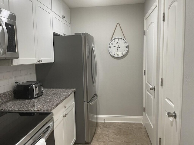 kitchen with white cabinets, backsplash, stainless steel appliances, and dark stone countertops