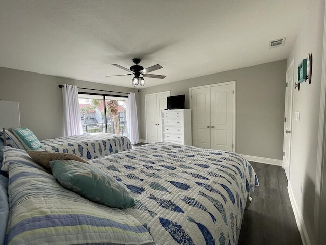 bedroom with ceiling fan, access to exterior, dark wood-type flooring, and multiple closets