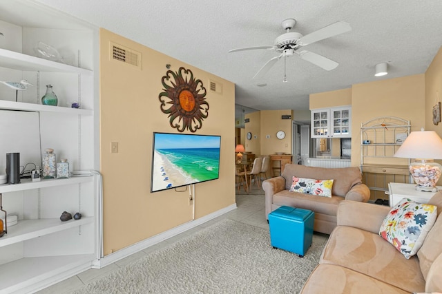 living room featuring ceiling fan, light tile patterned floors, and a textured ceiling