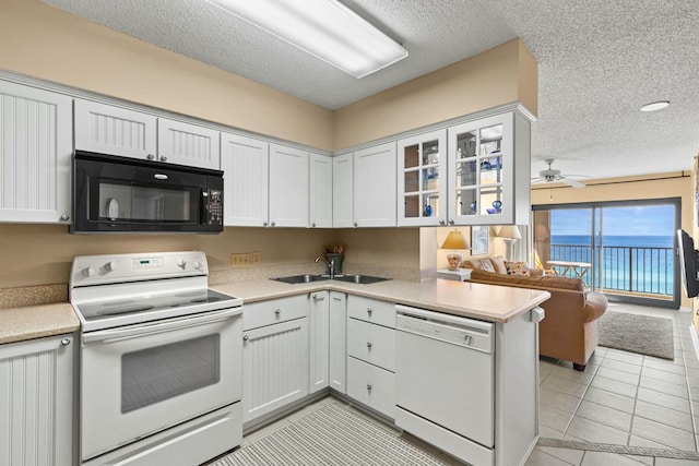 kitchen featuring a textured ceiling, white cabinetry, white appliances, and kitchen peninsula