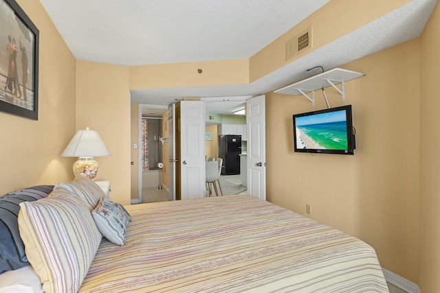 bedroom featuring black fridge and a textured ceiling