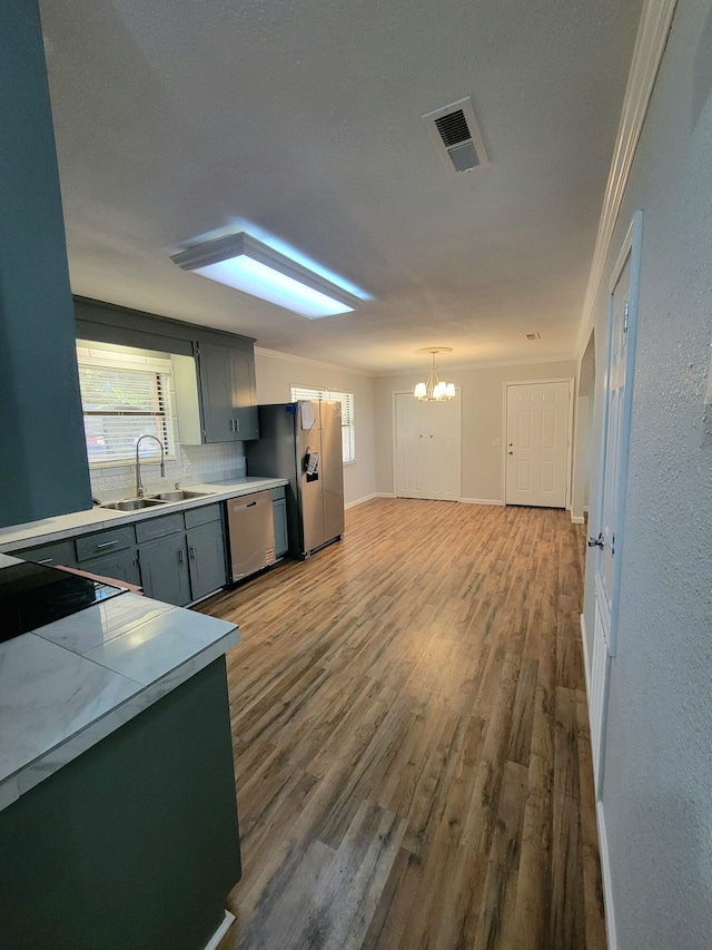 kitchen featuring sink, stainless steel appliances, backsplash, crown molding, and a chandelier