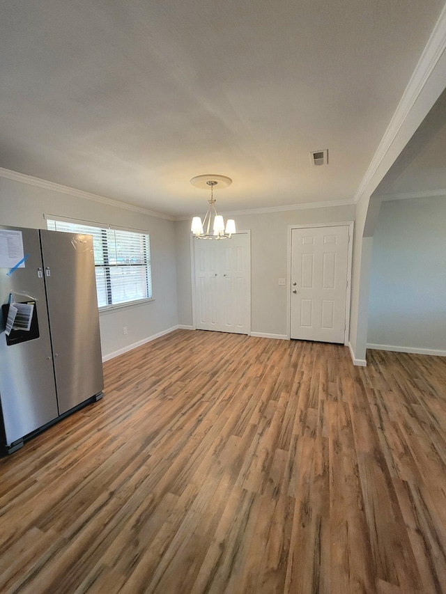 unfurnished dining area with a chandelier, hardwood / wood-style floors, and crown molding