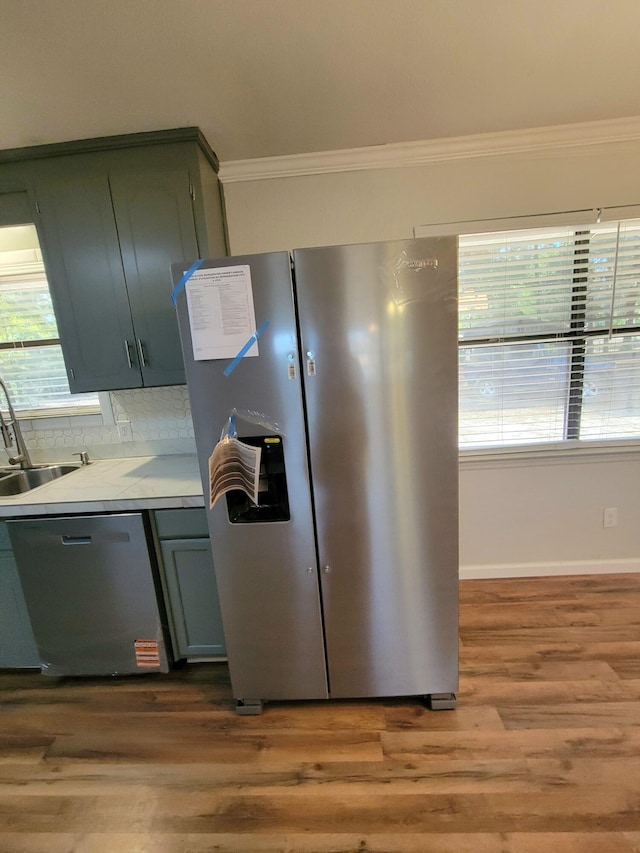 kitchen featuring sink, backsplash, crown molding, hardwood / wood-style floors, and appliances with stainless steel finishes