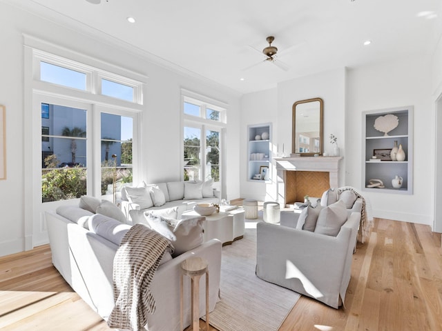 living room featuring ceiling fan, light hardwood / wood-style floors, and built in features