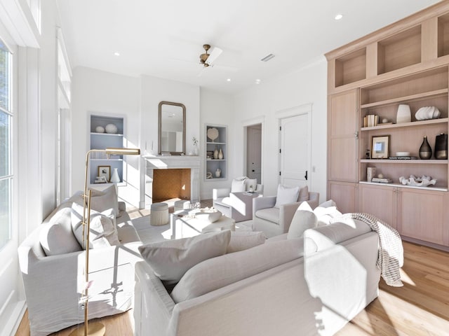 living room featuring ceiling fan, built in features, and light wood-type flooring