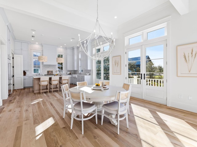 dining area with a wealth of natural light, an inviting chandelier, ornamental molding, and light hardwood / wood-style floors