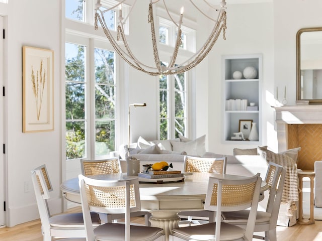 dining area with built in features, a chandelier, and light hardwood / wood-style floors