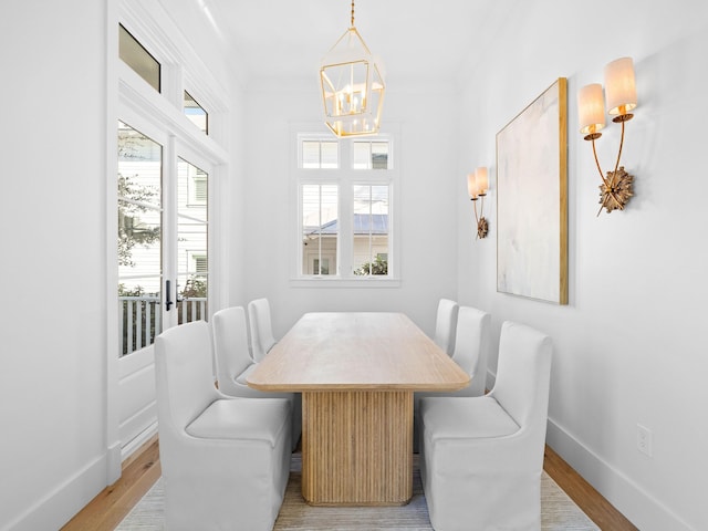 dining room with an inviting chandelier, crown molding, and light hardwood / wood-style flooring