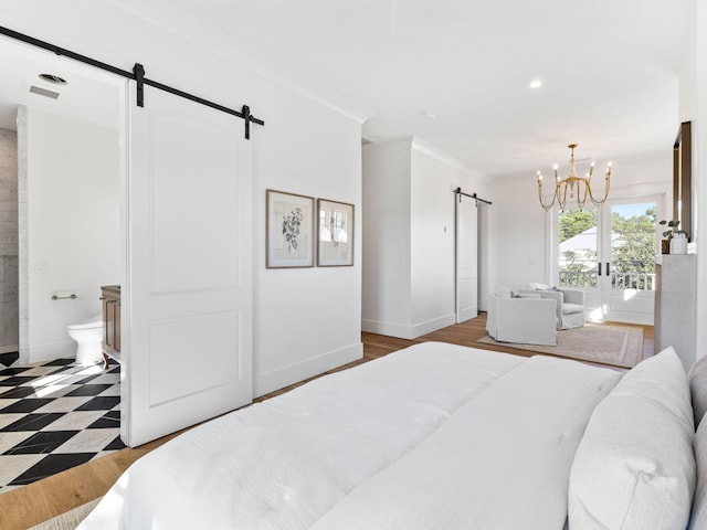 bedroom featuring a chandelier, crown molding, ensuite bath, and a barn door