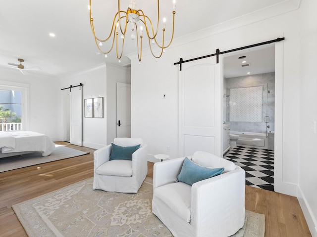 bedroom featuring crown molding, a barn door, hardwood / wood-style floors, and ensuite bath