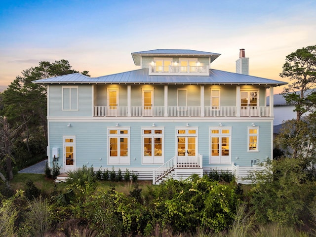 back house at dusk featuring a balcony