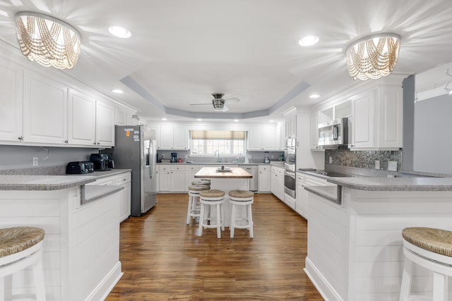 kitchen featuring kitchen peninsula, stainless steel appliances, white cabinetry, and a breakfast bar area