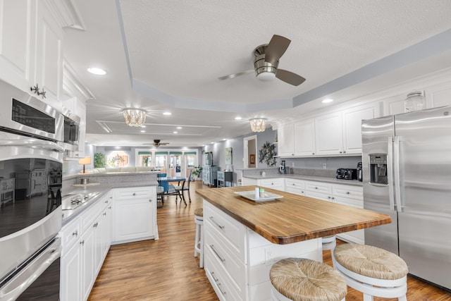 kitchen featuring a center island, a kitchen breakfast bar, stainless steel fridge with ice dispenser, kitchen peninsula, and white cabinets