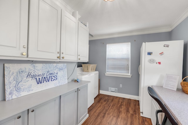 clothes washing area featuring dark hardwood / wood-style flooring, cabinets, crown molding, and washing machine and dryer