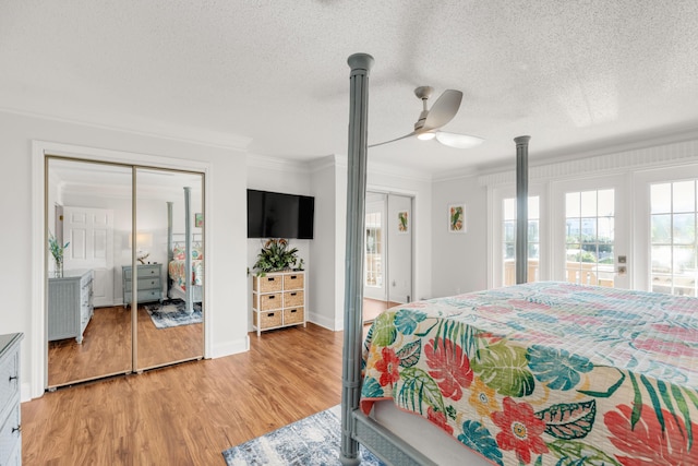 bedroom with ceiling fan, ornamental molding, a textured ceiling, and light wood-type flooring