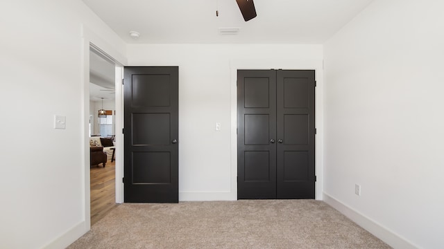 unfurnished bedroom with light carpet, a closet, and ceiling fan