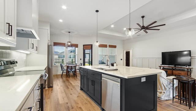 kitchen with white cabinets, appliances with stainless steel finishes, hanging light fixtures, and an island with sink