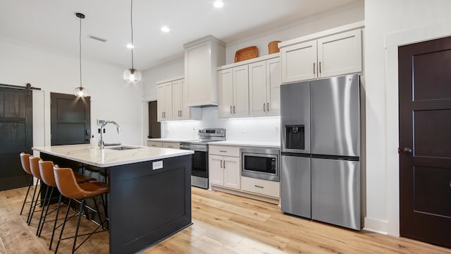 kitchen featuring white cabinets, a barn door, stainless steel appliances, and light hardwood / wood-style floors