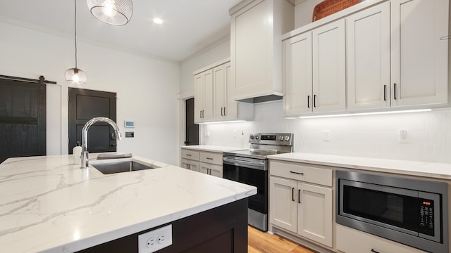 kitchen with pendant lighting, a barn door, stainless steel appliances, and white cabinetry