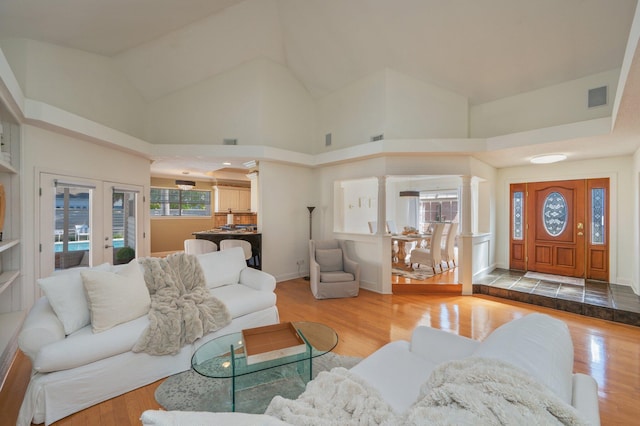 living room with french doors, light hardwood / wood-style floors, and high vaulted ceiling