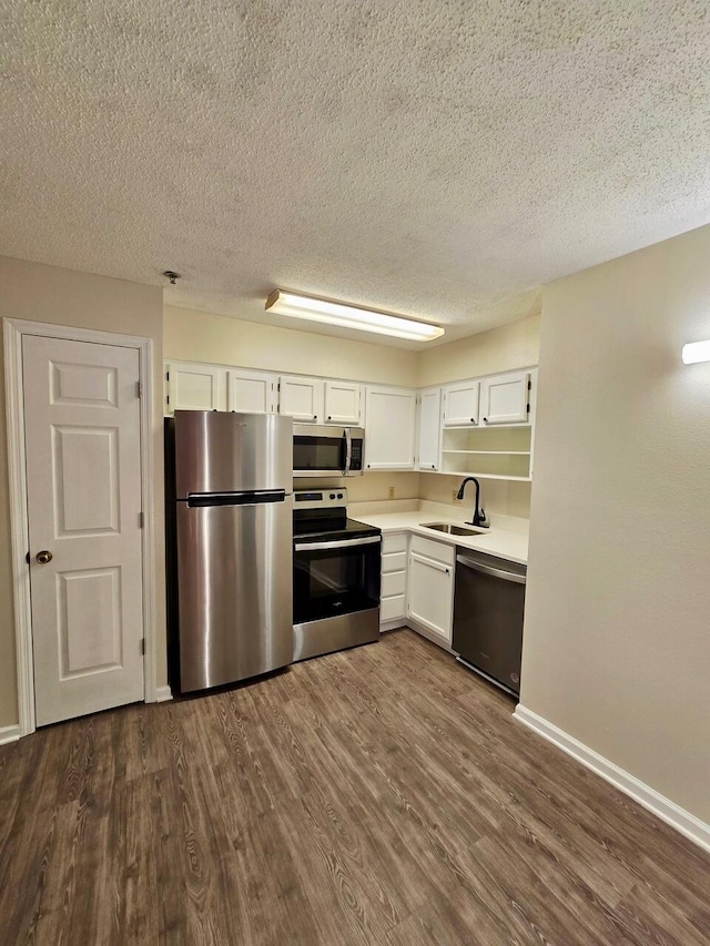 kitchen with appliances with stainless steel finishes, white cabinetry, a sink, and dark wood-type flooring