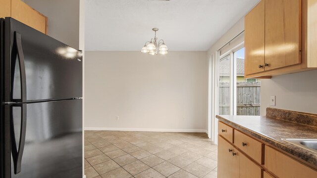 kitchen with black refrigerator, a chandelier, and hanging light fixtures