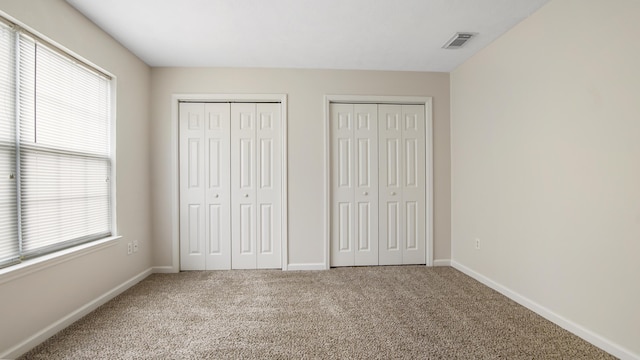 unfurnished bedroom featuring carpet flooring and multiple closets