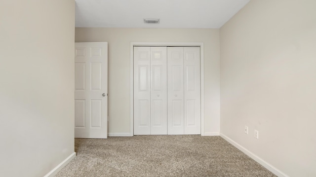 unfurnished bedroom with a closet and light colored carpet