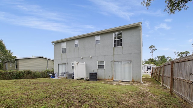 back of house with central AC unit and a yard