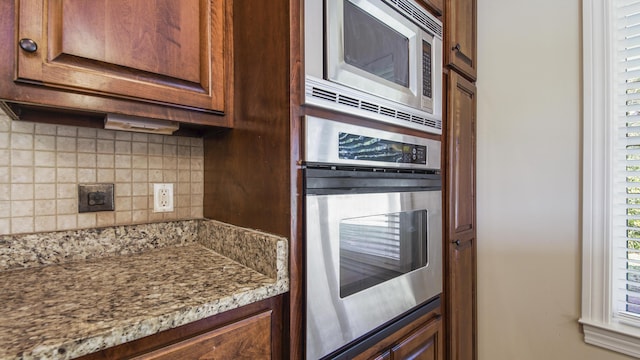 kitchen featuring decorative backsplash, light stone countertops, and appliances with stainless steel finishes