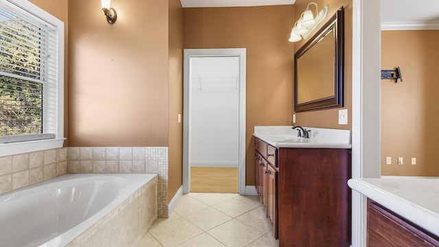 bathroom with tile patterned flooring, vanity, crown molding, and tiled bath