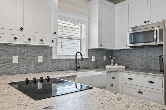 kitchen with white cabinetry, light stone countertops, and tasteful backsplash