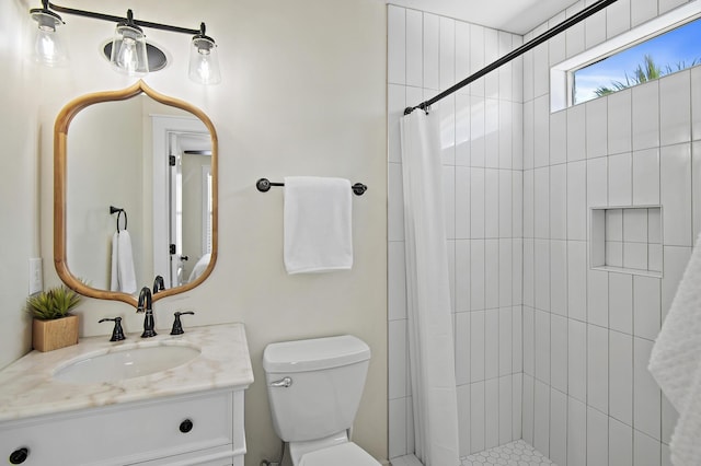 bathroom with vanity, toilet, and a tile shower