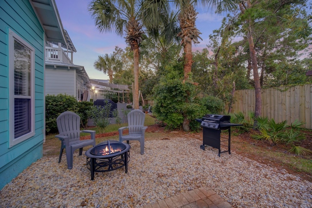 patio terrace at dusk featuring grilling area and a fire pit