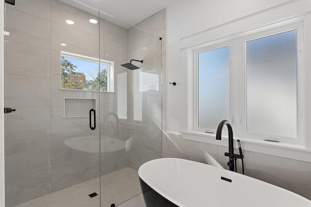 bathroom featuring a healthy amount of sunlight, sink, and plus walk in shower