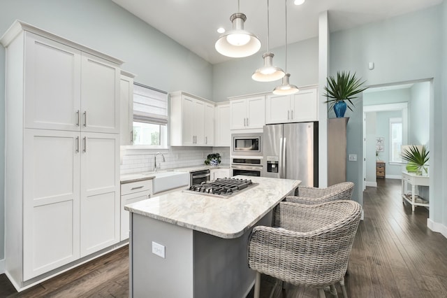 kitchen featuring white cabinetry, a center island, stainless steel appliances, dark hardwood / wood-style floors, and pendant lighting