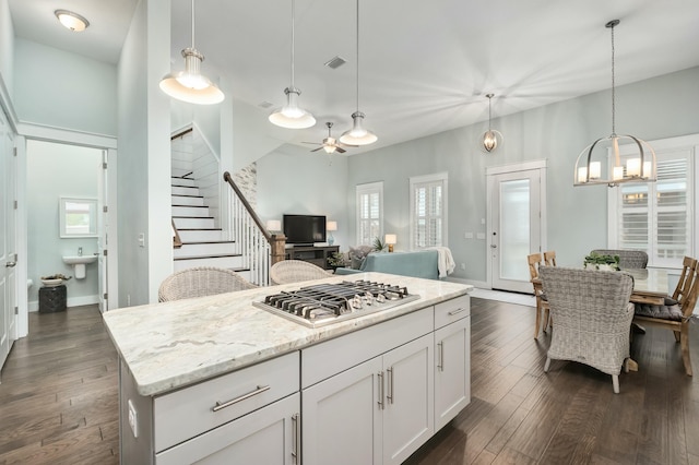 kitchen featuring a center island, white cabinets, dark hardwood / wood-style floors, decorative light fixtures, and stainless steel gas cooktop