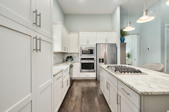 kitchen featuring stainless steel appliances, white cabinetry, dark wood-type flooring, and light stone counters