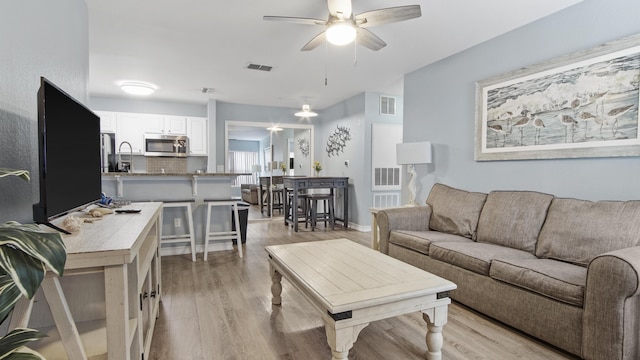 living room featuring ceiling fan and light hardwood / wood-style floors