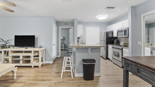 kitchen with white cabinets, light wood-type flooring, and appliances with stainless steel finishes