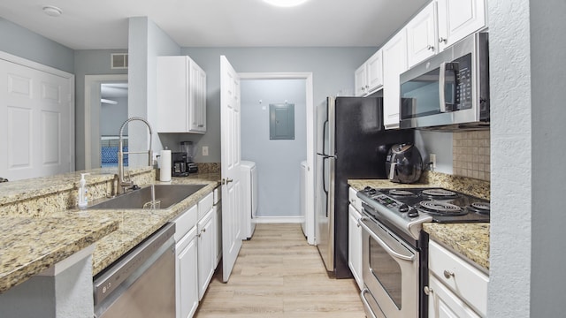 kitchen featuring sink, appliances with stainless steel finishes, light hardwood / wood-style floors, light stone counters, and white cabinetry