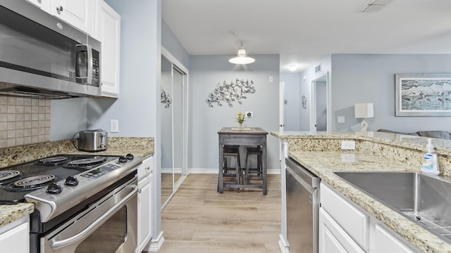 kitchen featuring sink, decorative backsplash, light wood-type flooring, appliances with stainless steel finishes, and white cabinetry