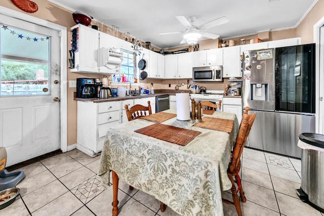 kitchen featuring stainless steel appliances, ceiling fan, crown molding, light tile patterned floors, and white cabinets