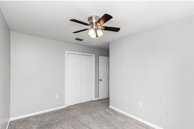 unfurnished bedroom featuring a textured ceiling, a closet, ceiling fan, and light colored carpet