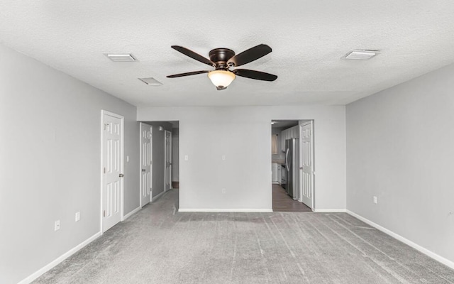 unfurnished bedroom featuring carpet flooring, a textured ceiling, ceiling fan, connected bathroom, and stainless steel refrigerator