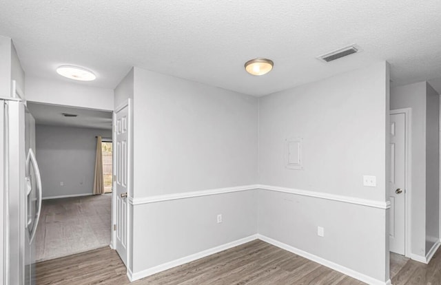 spare room featuring wood-type flooring and a textured ceiling